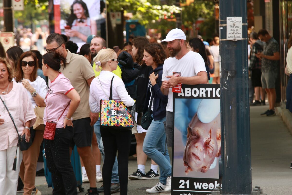 Pro-life man in a baseball cap having a discussion with Vancouverites about abortion.